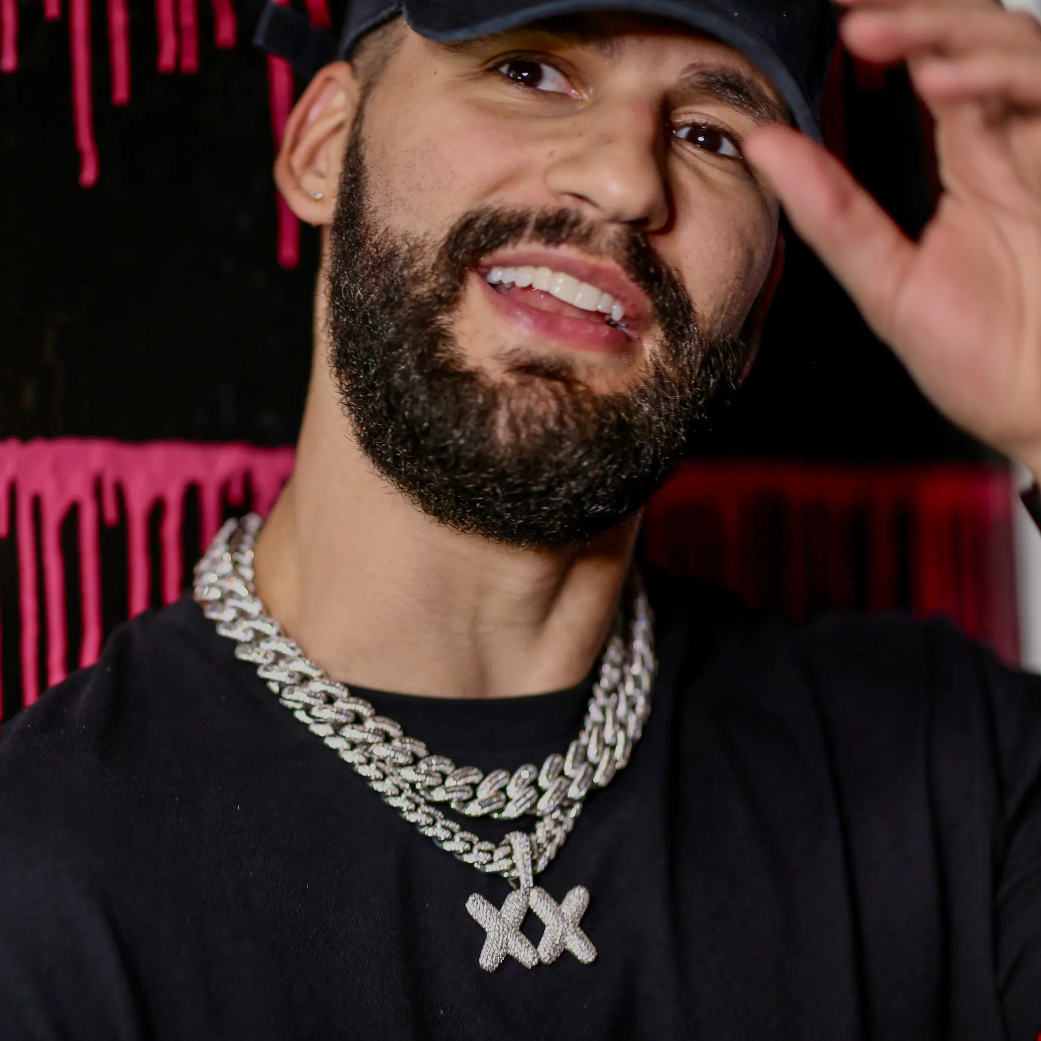 Man wearing a black shirt and large chain necklace with a dark background