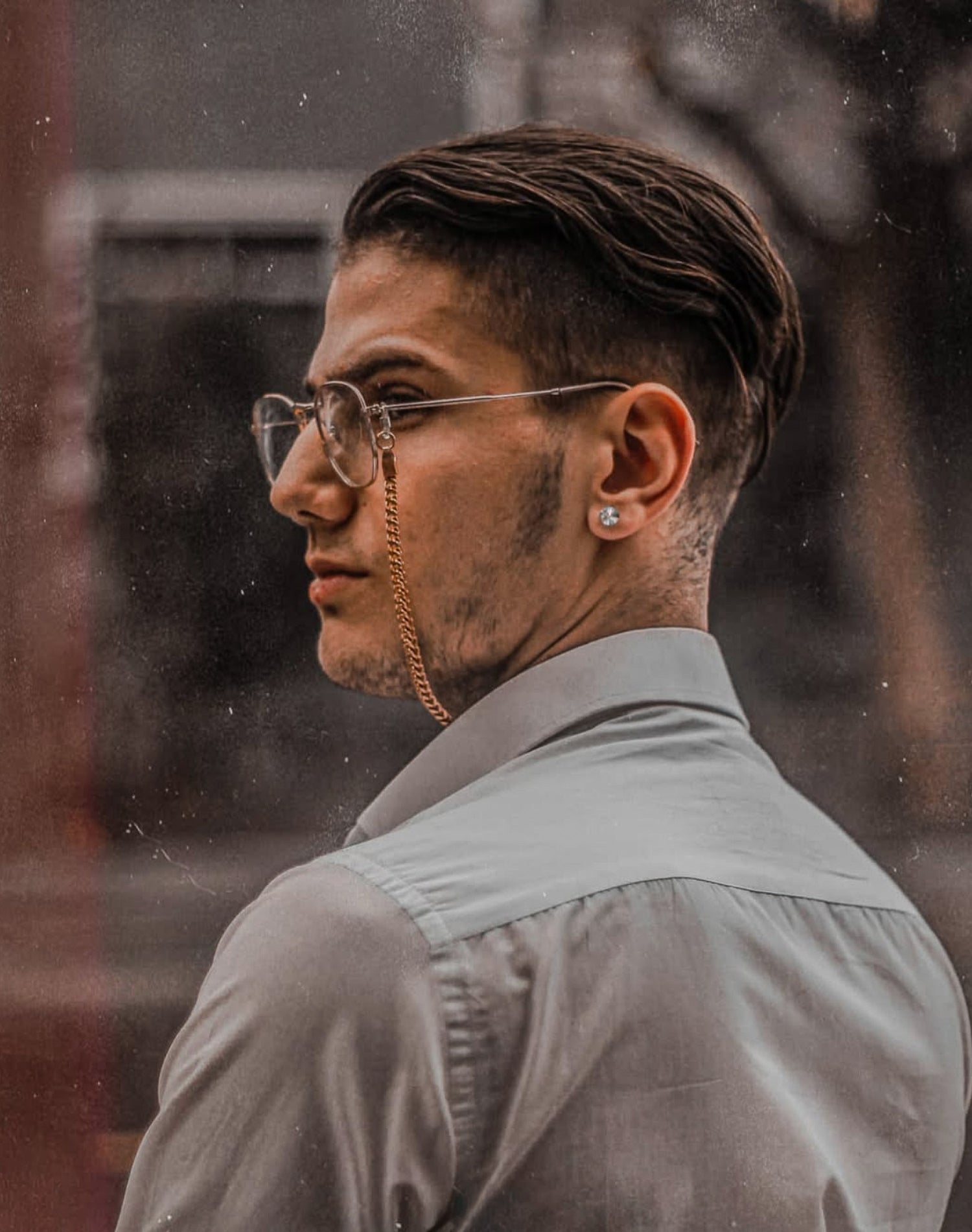 Man with stylish haircut and glasses looking over his shoulder