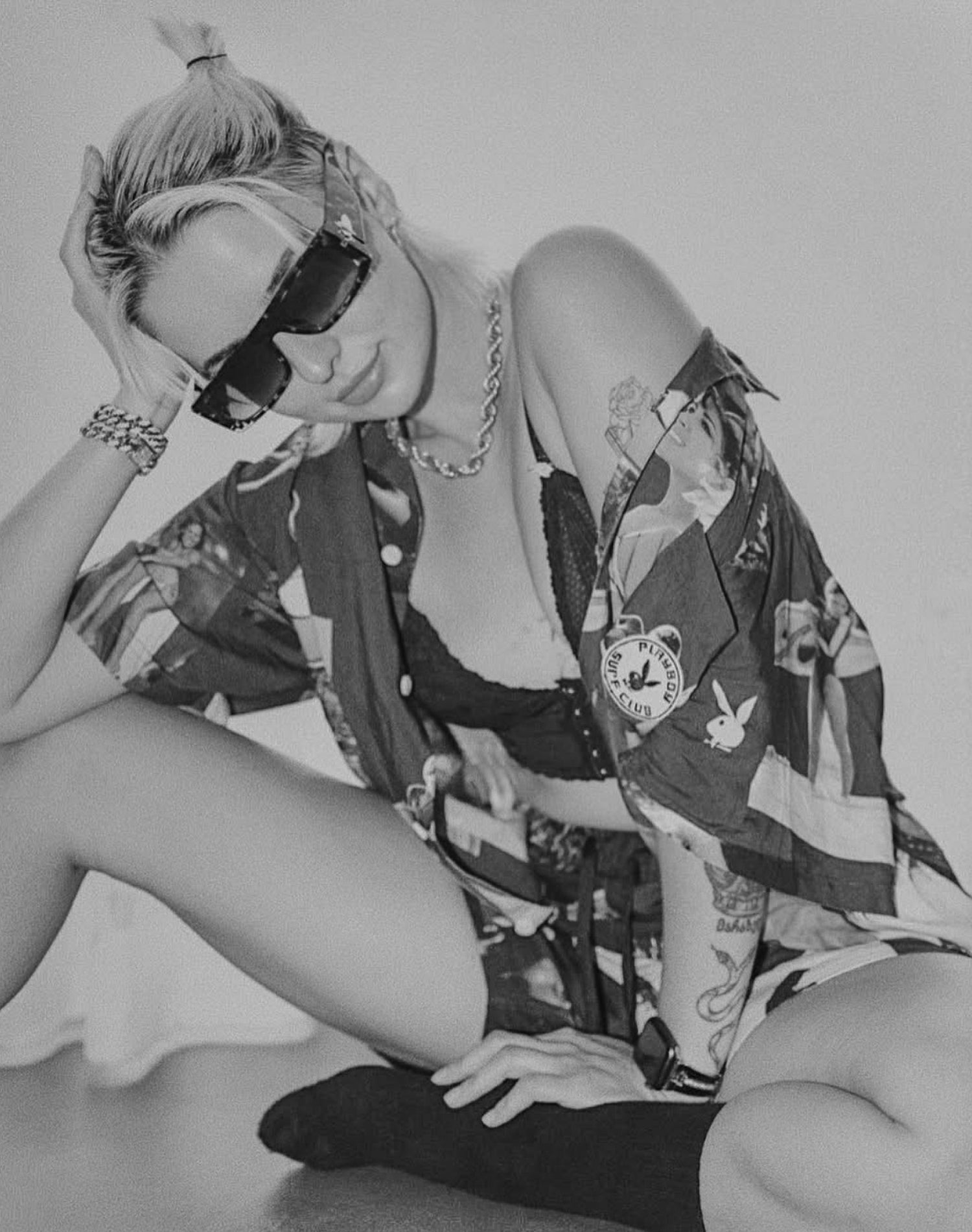 Person wearing a patterned kimono-style garment with sunglasses and a neutral background