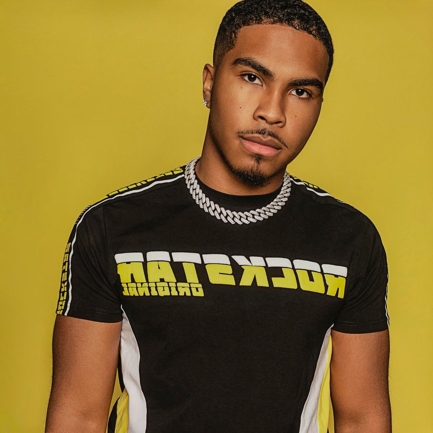 Man wearing a black t-shirt with yellow and white text on a yellow background