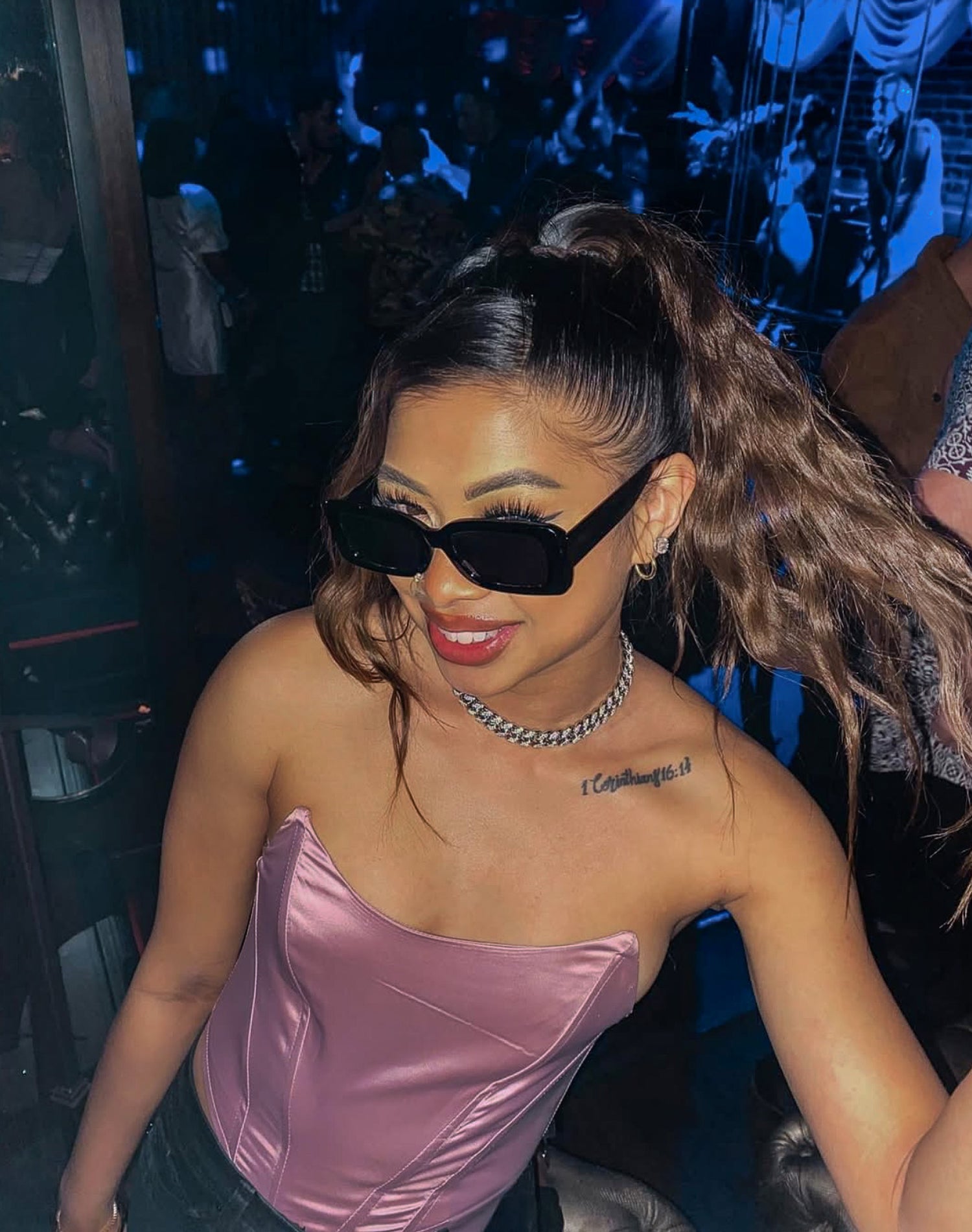 Woman wearing sunglasses and a pink top in a club setting