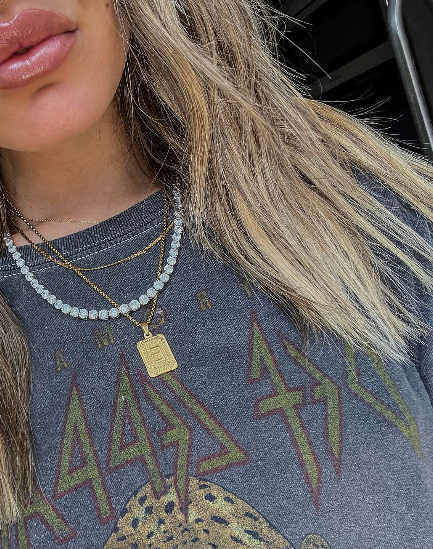 Close-up of a person wearing layered necklaces with a graphic t-shirt in the background