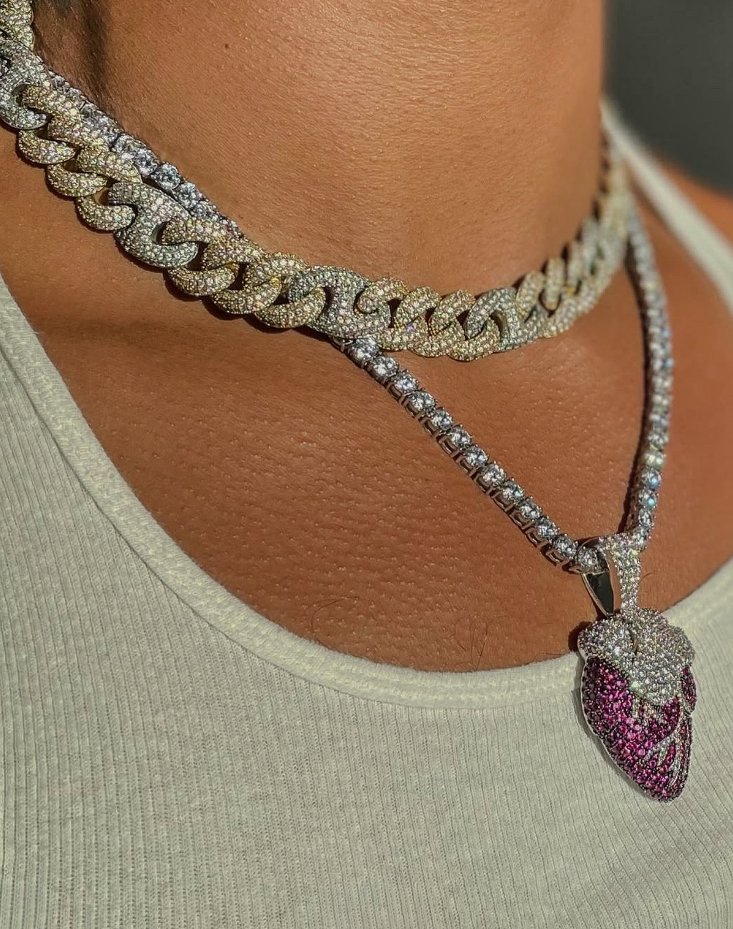 Close-up of a person wearing a diamond-encrusted necklace with a pendant.